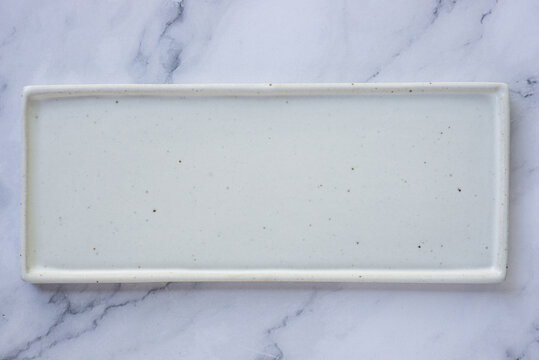 rectangle white handmade ceramic plate on marble table background.