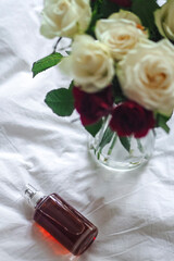 Open bottle next to a vase holding flowers