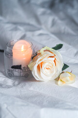 Rose and candle on a bedsheet with airplane in background