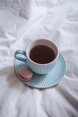 Tea cup and saucer rest on a bed