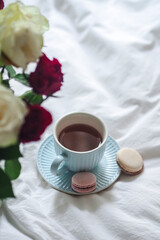 WWhite bed with roses and a cup of coffee on white linen