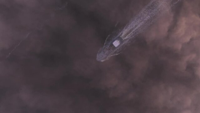 Aerial view of foggy sunrise over fishing vessel in tranquil waters, Harlingen, Friesland, Netherlands.