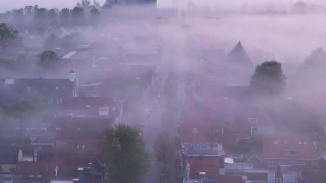 Aerial view of foggy sunrise over church and city rooftops, Workum, Friesland, Netherlands.