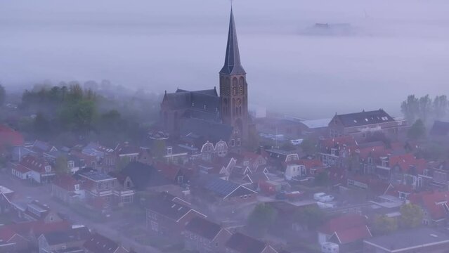 Aerial view of foggy morning over historic church and rooftops in Workum, Friesland, Netherlands.