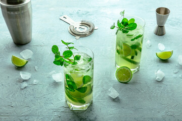 Mojito cocktail. Summer cold drink with lime, fresh mint, and ice. Cool beverage, with a shaker and other mixing accessories