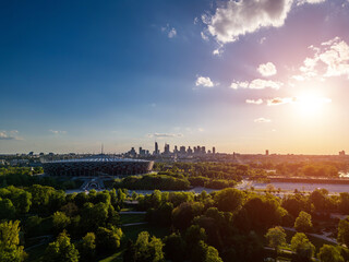 panorama of Warsaw city skyline and PGE Narodowy stadium at sunset, skyscrapers of downtown and green park, aerial top view
