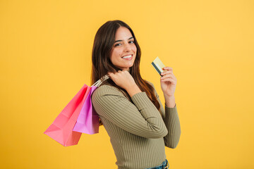 Portrait of a young caucasian customer woman holding shopping bags and a credit card, contemplating...