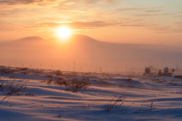 Winter arctic landscape. Beautiful sunset over the tundra and the snow-capped mountain. Cold frosty winter weather. Nature of Siberia and the Russian Far East. Chukotka, Far North of Russia, Arctic.