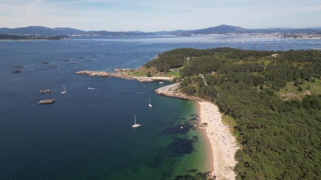 Aerial view of beach, ocean, forest, boats, and coastline in A Illa de Arousa, Pontevedra, Spain.