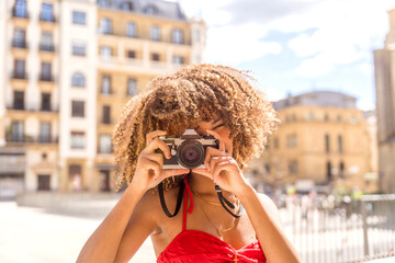 Brunette woman taking a photo and smiling visiting a city
