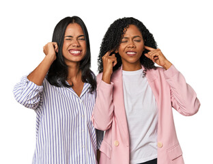 Young Latin businesswomen in studio covering ears with fingers, stressed and desperate by a loudly...