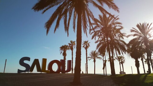 colorful letters of Salou town, palm trees andl beach at sunset, Catalonia, Spain 4k