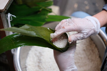 hands making Zongzi (rice dumpling or sticky rice dumpling). traditional Chinese food in Dragon...