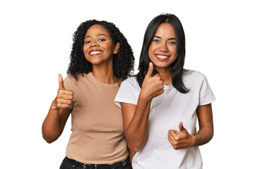 Young Latin friends in studio raising both thumbs up, smiling and confident.