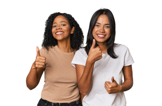 Young Latin friends in studio raising both thumbs up, smiling and confident.