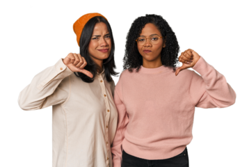 Young Latin friends together in studio showing thumb down, disappointment concept.