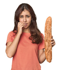 Middle Eastern woman holding bread loaf biting fingernails, nervous and very anxious.
