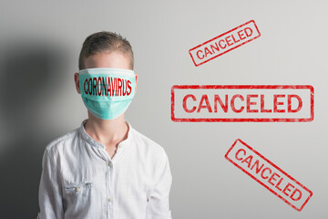 Boy in a medical mask with red inscription CORONAVIRUS on his face on bright background. Epidemic...