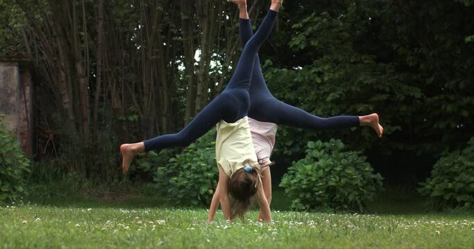 Super slow motion of carefree happy teen girls sisters friends having fun to make a wheel together in garden outside his house on a sunny day. Childhood, family fun, freedom and happiness, active kids