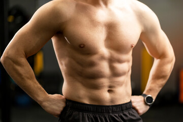 Fototapeta premium Closeup portrait of pumped-up, muscular brutal male body, naked torso standing in gym