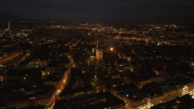 Stunning aerial view of St Pierre Cathedral in Geneva at night, showcasing the illuminated urban landscape and street lights