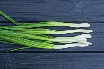 a bunch of fresh white green onions lie on a black wooden table
