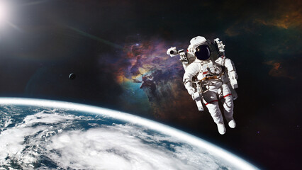 Cosmonaut in outer space against Earth planet. Elements of this image furnished by NASA.