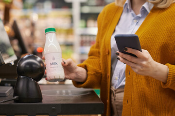 Close up of unrecognizable woman scanning milk bottle while using self checkout service grocery...