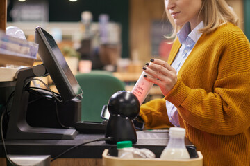 Close up of unrecognizable woman scanning dairy cream bottle while using self checkout  in...