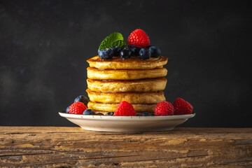 Delicious pancakes with fresh berries on rustic wooden table. Food concept.