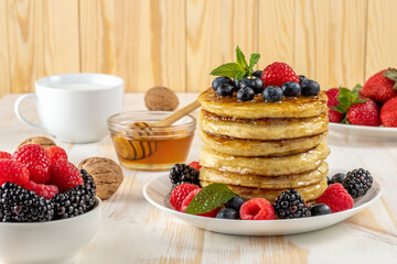 Delicious pancakes with fresh berries on white wooden table. Food concept.