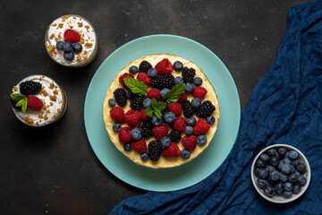 Homemade cake with fresh berries and sweet desserts on dark background.