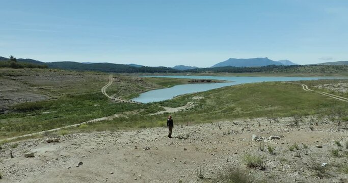 Aerial view of woman walking by Embalse de Guadalteba in mountainous landscape, Campillos, Andalusia, Spain.