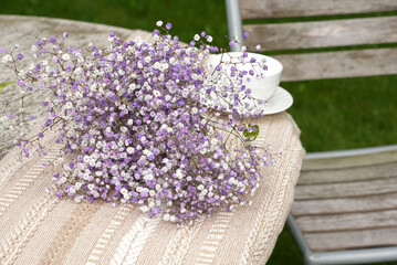 Bouquet on outdoor wooden bench in afternoon light with empty chair