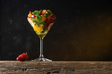 Fruit cocktail in martini glass on wooden table. Food vegan concept.