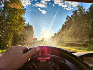 Car salon, windshield, hand of woman on steering wheel and landscape. View from seat of driver on...