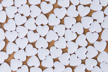 white pills in the shape of a heart on a brown background.