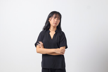 Portrait of unpleasant Asian woman in casual shirt keeping arms crossed and looking at camera with skeptical and distrustful look. Isolated image on white background
