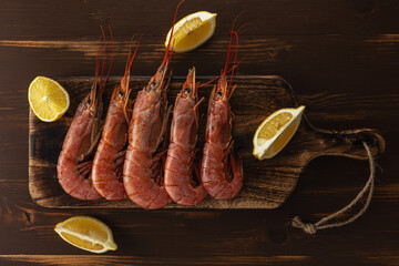 Fresh shrimps on wooden background with lemon slice. Seafood background.