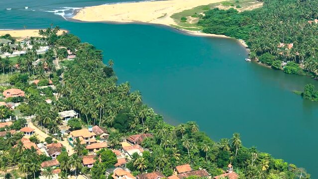 Aerial view of River Maha Oya with huts, palm trees, and houses, Negombo, Sri Lanka.