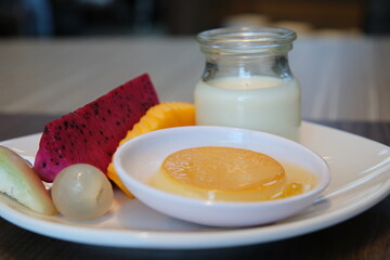 dairy products with fruits yogurt caramel jelly with on plate asian tropical fruits Caramel custard pudding with mint and caramel syrup isolated on white background. Flan dessert made of eggs