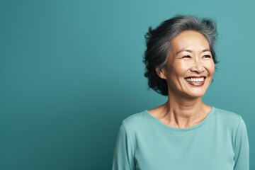 Teal Background Happy Asian Woman Portrait of Beautiful Older Mid Aged Mature Smiling Woman good mood Isolated Anti-aging Skin Care Face Beauty Product Banner with copyspace 