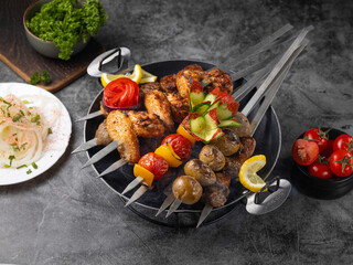 Chicken kebab skewers on a plate over grey slate, stone or concrete background . Top view with copy space.