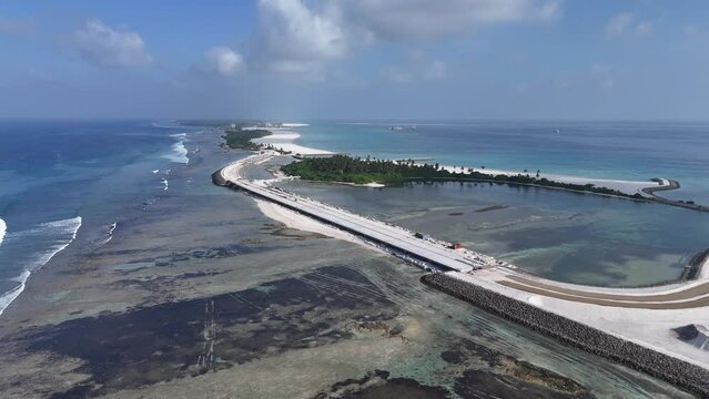 Aerial view of coastal development with bridge, road, and palm trees in Maradhoo, Addu Atoll, Maldives.