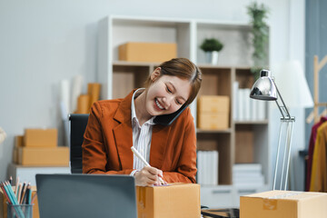 Shipping shopping online ,woman start up small business owner writing address on cardboard box at workplace.small business entrepreneur SME or freelance  woman working with box at home.