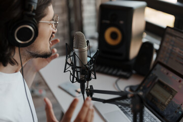 Man recording a podcast with a professional microphone and headphones in a modern home studio setup.