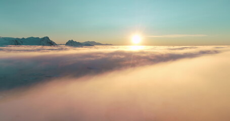 Aerial view bright colorful sunrise over morning clouds and fog. Mountain range in background. Drone flight. Breathtaking scene orange sun, blue sky. Nature background perfect landscape wallpaper