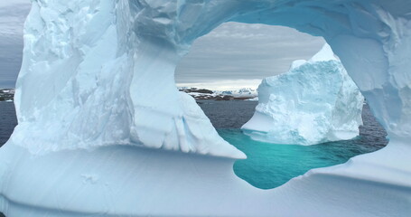 Large iceberg melting hole inside drifting polar ocean. Drone flight in ice floe cave floating...