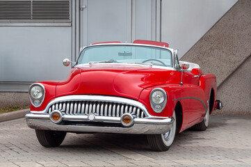 A red retro car is parked near the wall.