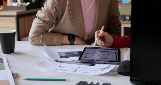 Architects discussing layout on digital tablet, focusing on floor plan details. Meeting modern technology integration in architectural design. Collaborative workflow in contemporary office setting.